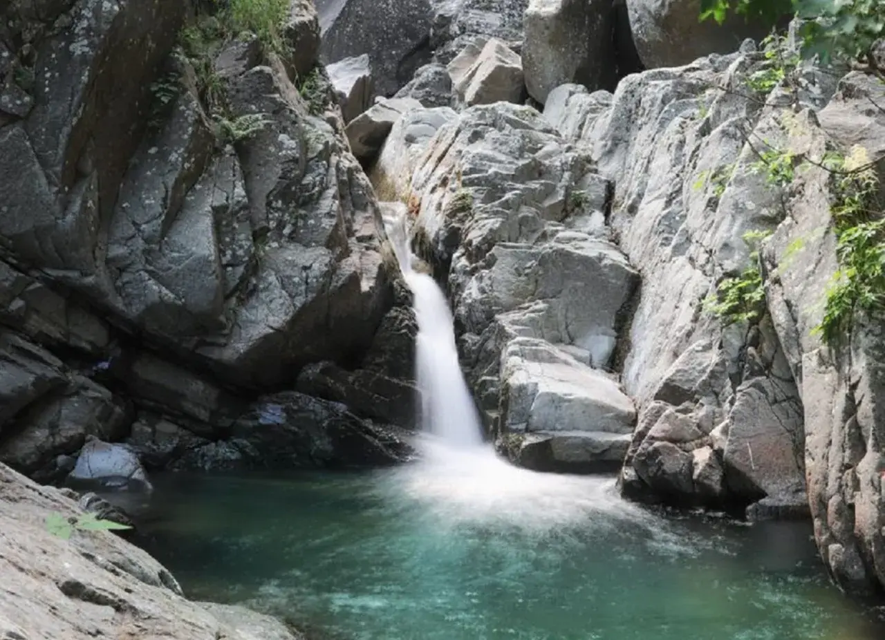 Cascate naturali in Lunigiana, con acqua cristallina che scende tra rocce grigie e vegetazione rigogliosa. Un angolo di paradiso selvaggio.