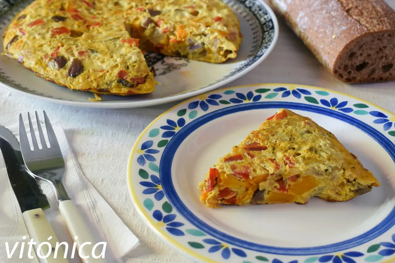 Deliciosa tortilla de berenjena con pimientos y calabaza, servida en un plato decorado.