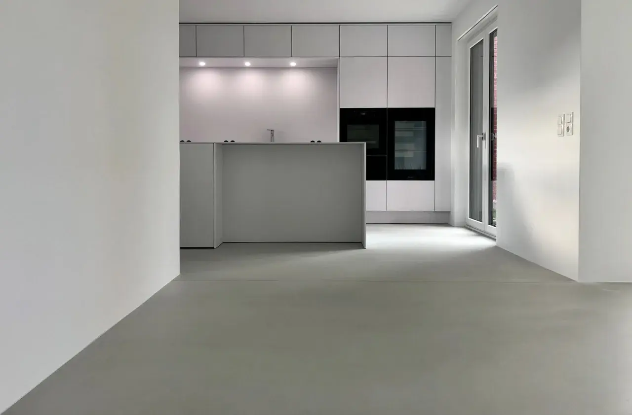 Moderne Küche mit minimalistischer Insel und Einbaugeräten. Der fugenlose Boden erfahrungen sind positiv, da er leicht zu reinigen ist und einen eleganten Look bietet.