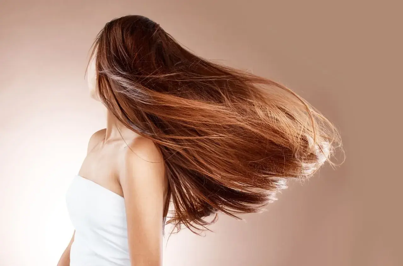 Mujer con cabello largo y castaño moviéndose con el viento. ¿Cuánto crece el pelo en un año mujer?