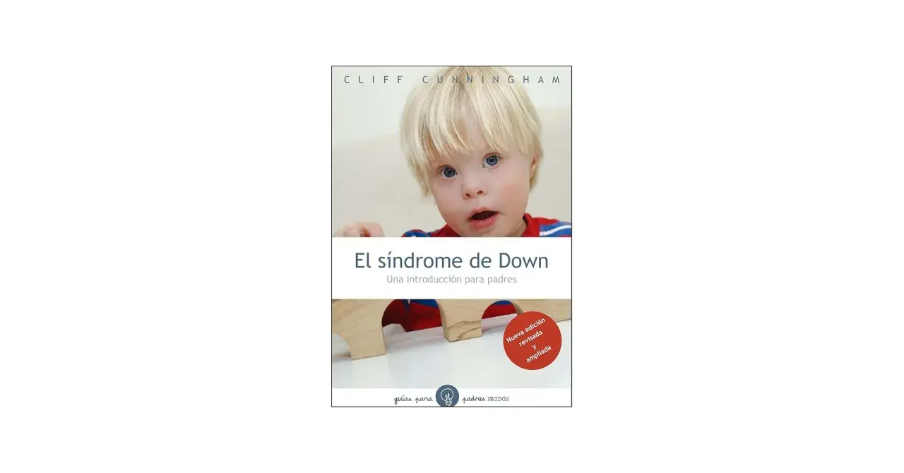 Un niño con síndrome de Down mira a la cámara. El libro "El síndrome de Down: Una introducción para padres" se muestra en la imagen.
