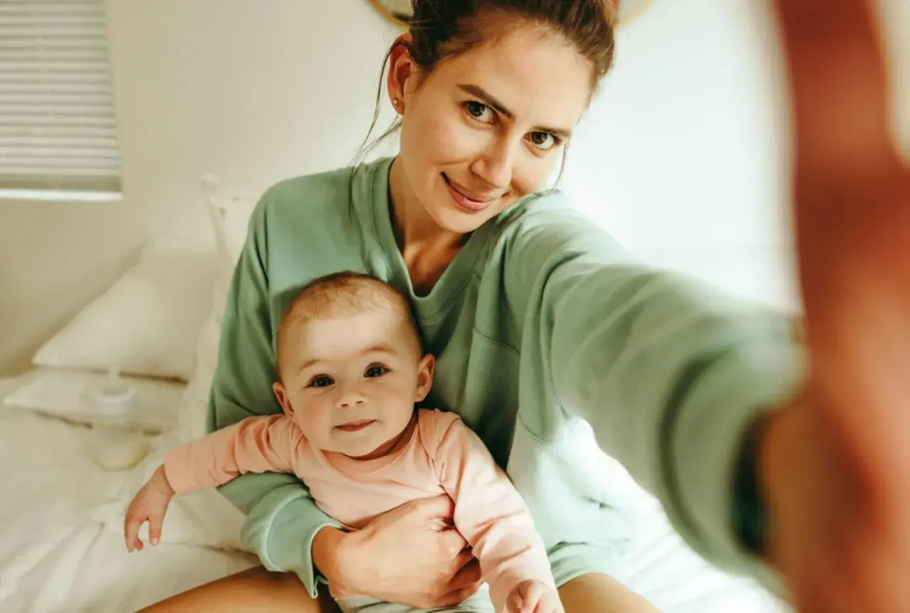 Uśmiechnięta mama z dzieckiem na rękach, czuje, kiedy macierzyństwo zaczyna cieszyć.