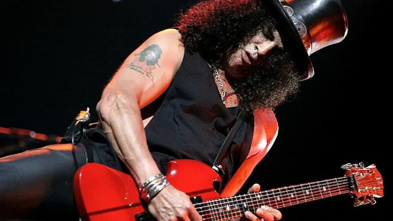Slash w cylindrze gra na czerwonej gitarze, jakby śpiewał "sweet child o' mine".