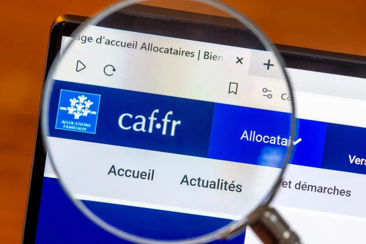 Loupe sur l'écran d'un ordinateur affichant le site caf.fr, page d'accueil des allocataires. L'accès aux informations est facilité.