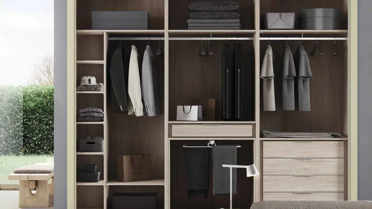 Un armario moderno y funcional, ideal para quienes buscan cómo diseñar un armario con estilo. Ropa colgada, cajones y estantes organizados.