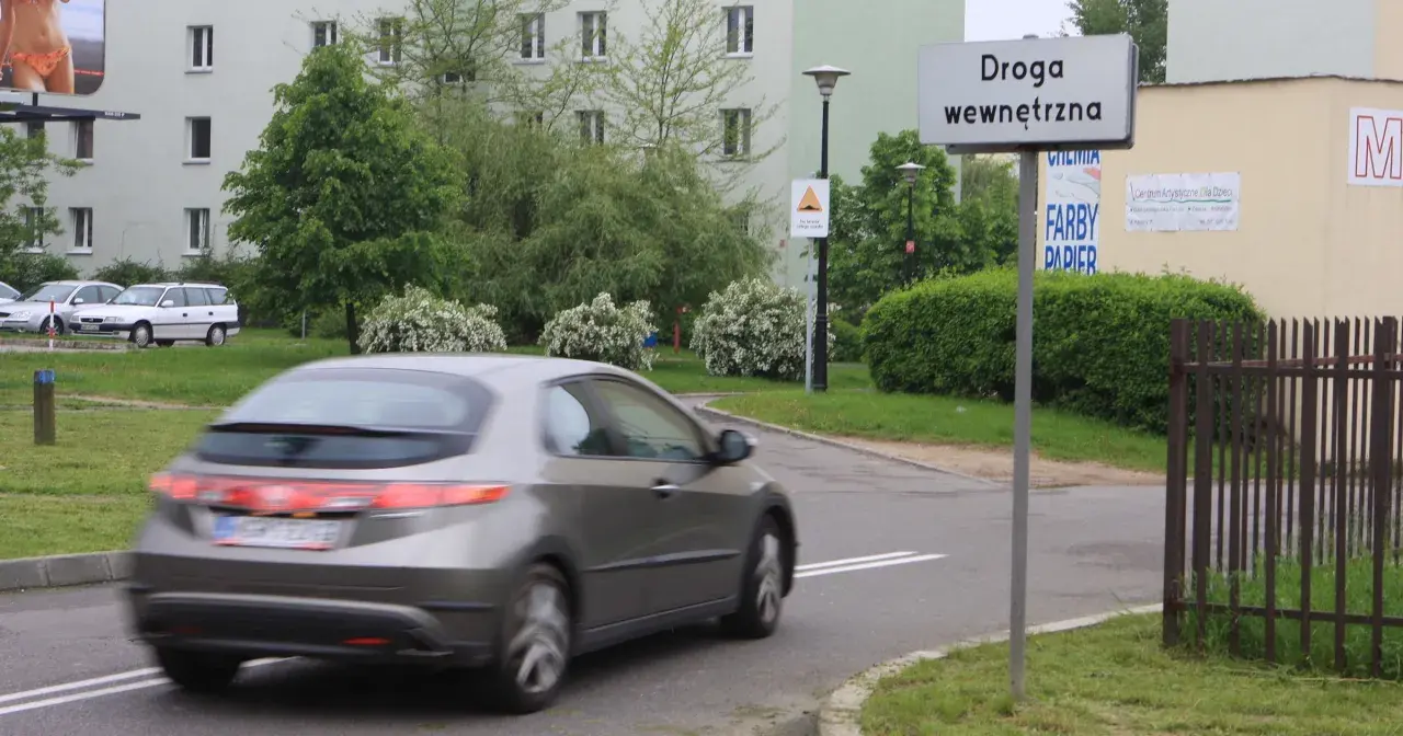 Znak "Droga wewnętrzna" informuje o zasadach ruchu na tym terenie. Samochód w ruchu.