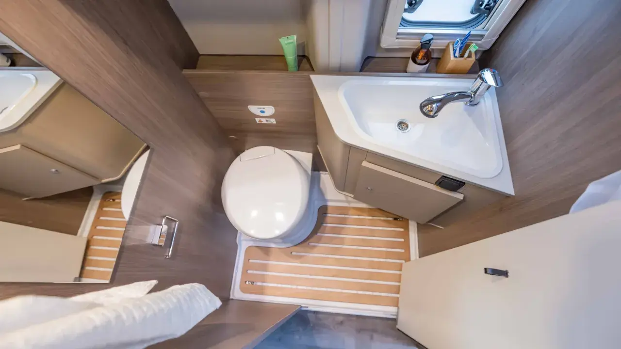 Salle de bain arrière de camping-car : toilette, lavabo et douche intégrée. Pratique pour les voyages.