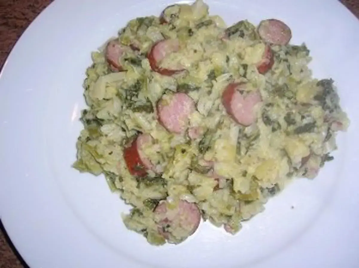 Herzhaftes Gericht mit Kartoffeln, Grünkohl und deftigen Wurstscheiben, die wirsing untereinander gemischt sind.