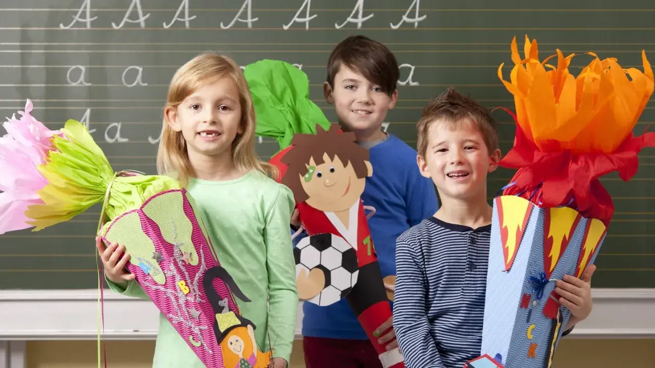Drei Kinder mit Schultüten vor einer Tafel. Die Schultüten sind bunt und thematisch gestaltet, passend zu den herbstlichen angebote kita.