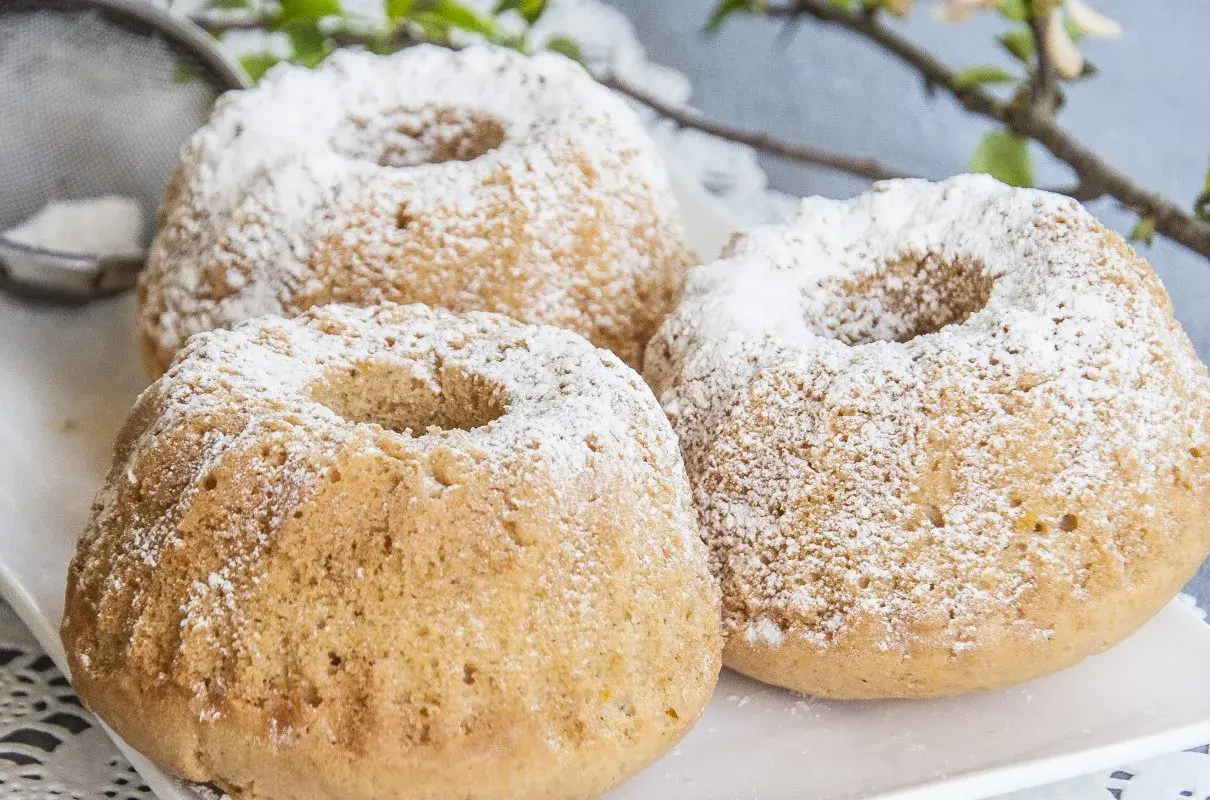 Trzy puszyste muffinki piaskowe posypane cukrem pudrem, gotowe do podania.
