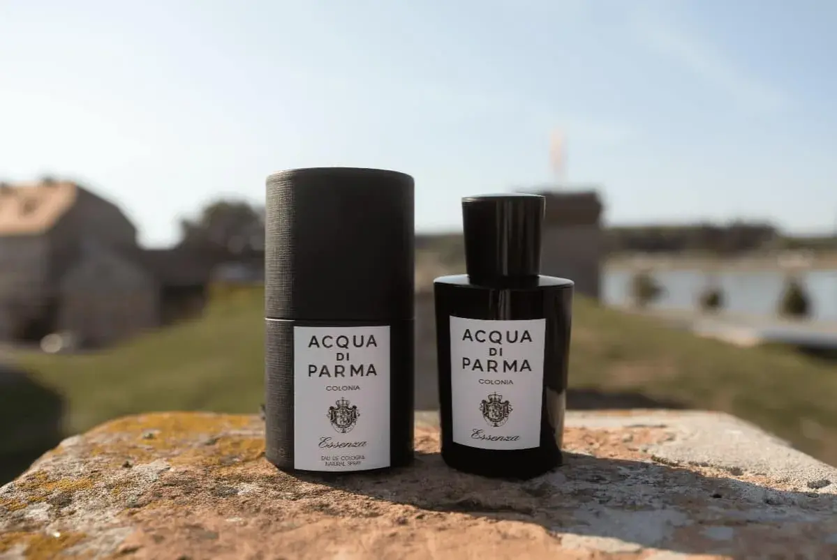 Elegancka butelka i opakowanie Acqua di Parma Essenza na tle malowniczego krajobrazu.