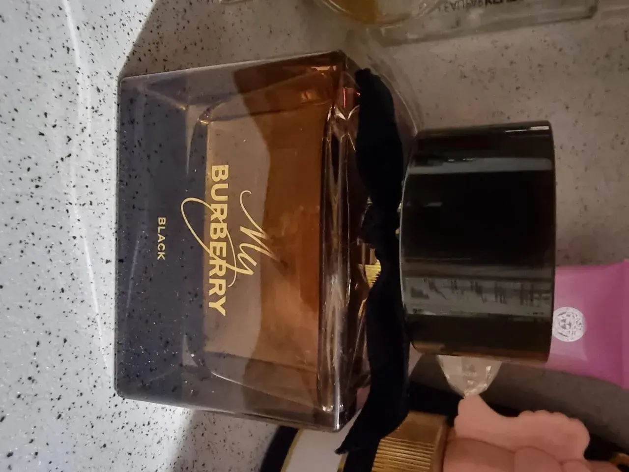 Elegancka butelka perfum My Burberry Black z czarną wstążką i złotym napisem.