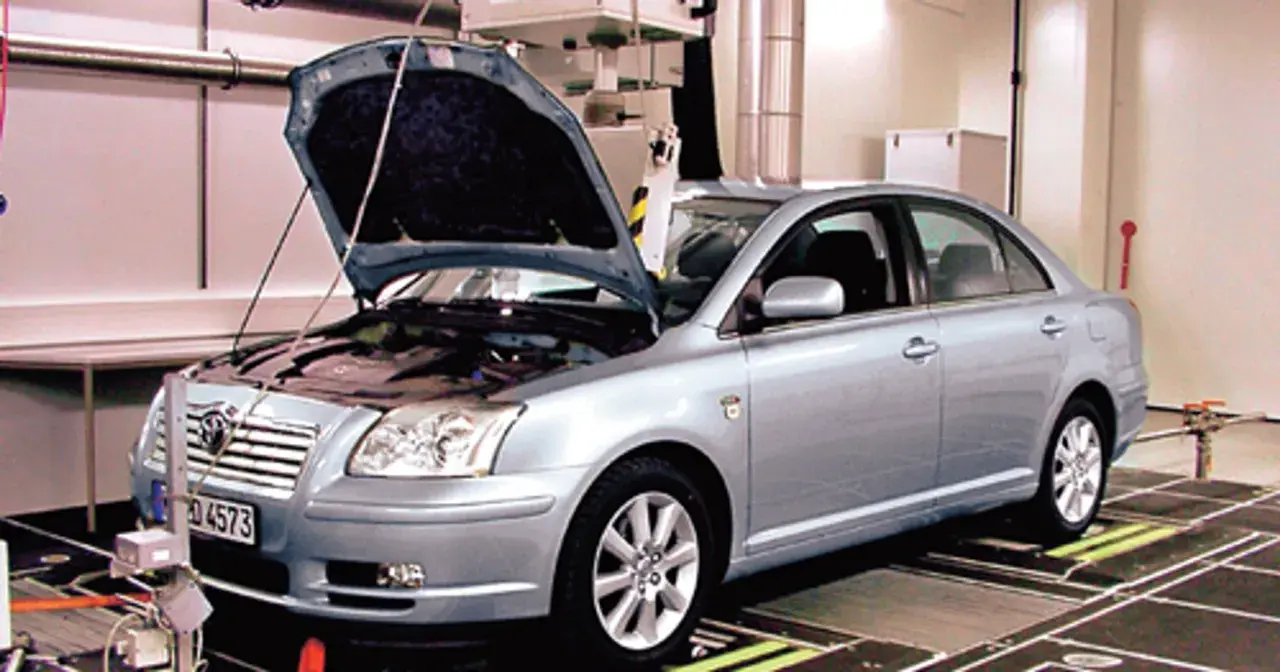 Srebrna Toyota Avensis 2.0 D4D z otwartą maską stoi na stanowisku diagnostycznym.
