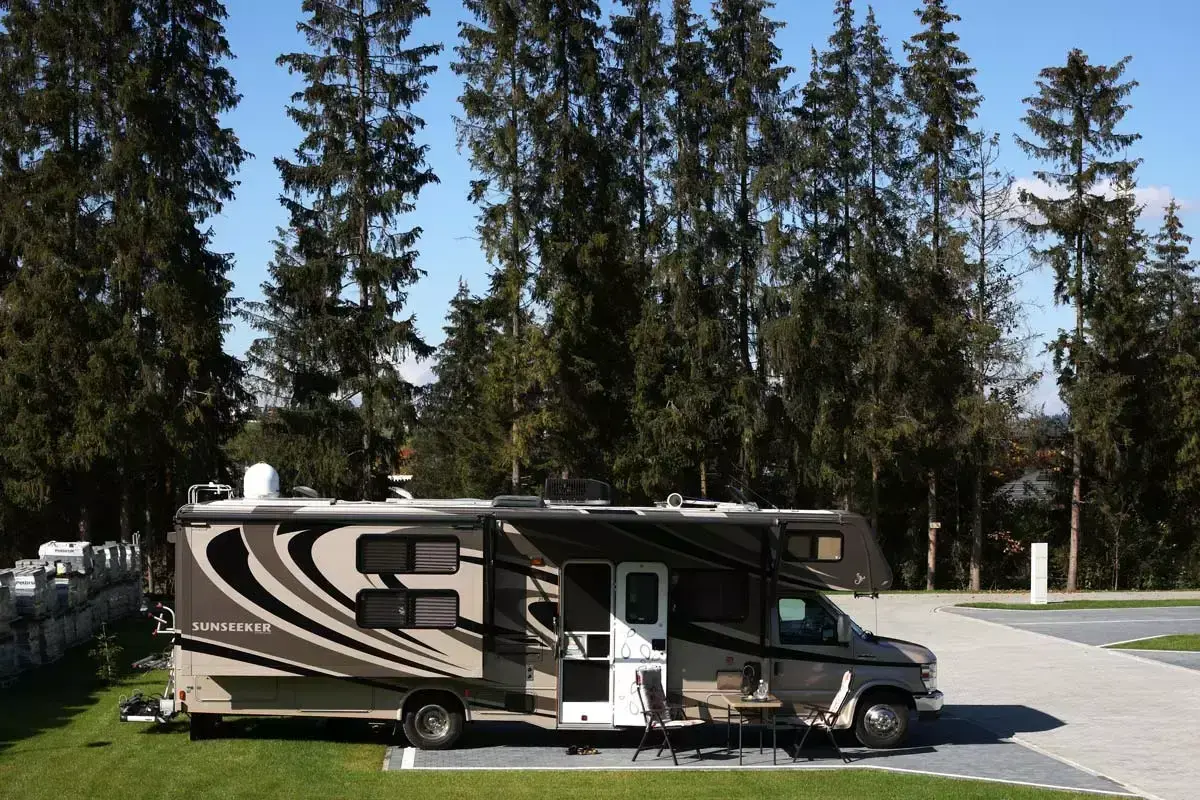 Kamper Sunseeker zaparkowany na campingu Gorący Potok, otoczony wysokimi sosnami.