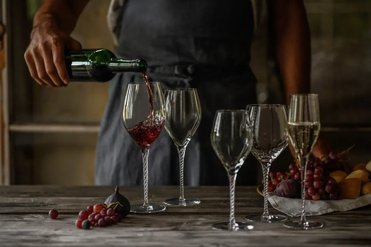 Skutki napowietrzania wina (dekantacja) widoczne podczas przelewania do karafki. Wino w kieliszku, obok winogrona i figi.