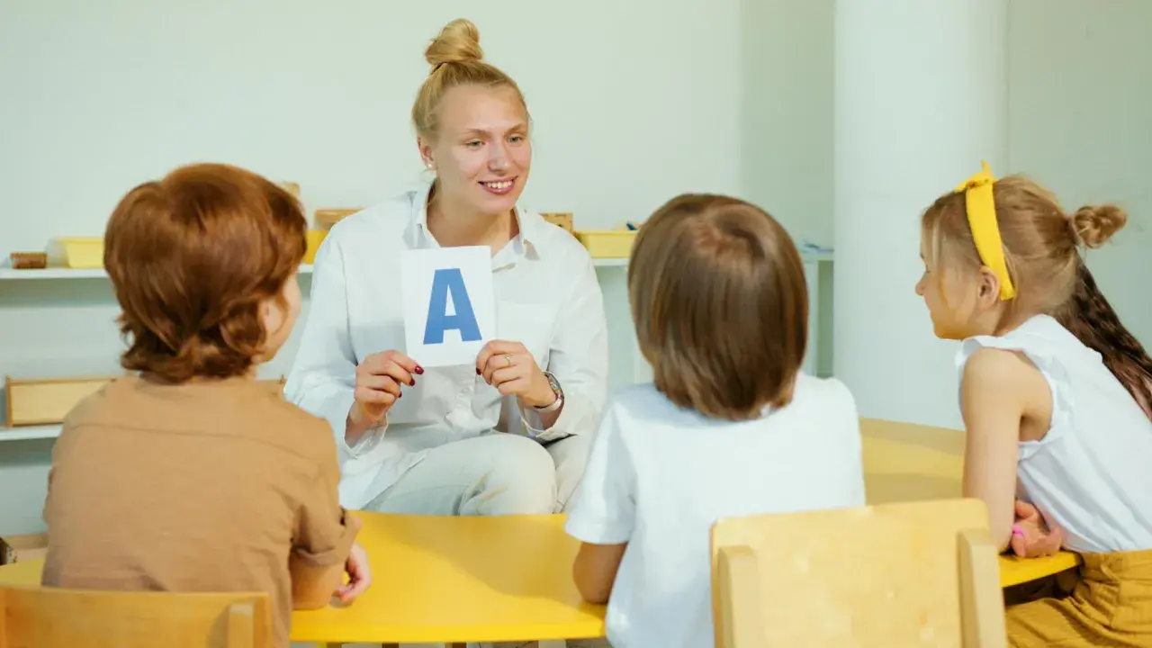 Nauczycielka pokazuje dzieciom literę "A" na karcie.