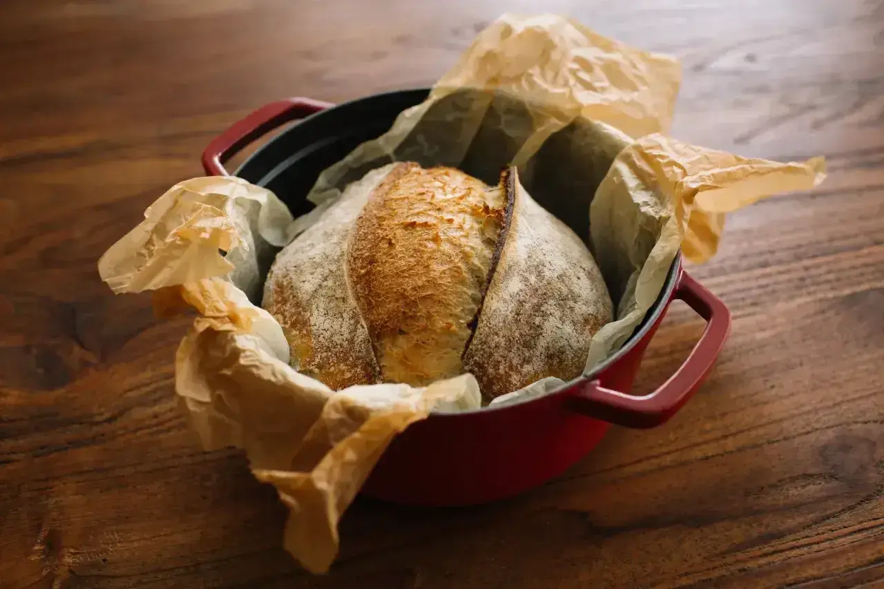 Chleb na zakwasie w czerwonym naczyniu żeliwnym, gotowy do pieczenia. Idealna temperatura pieca chleb to klucz do chrupiącej skórki.