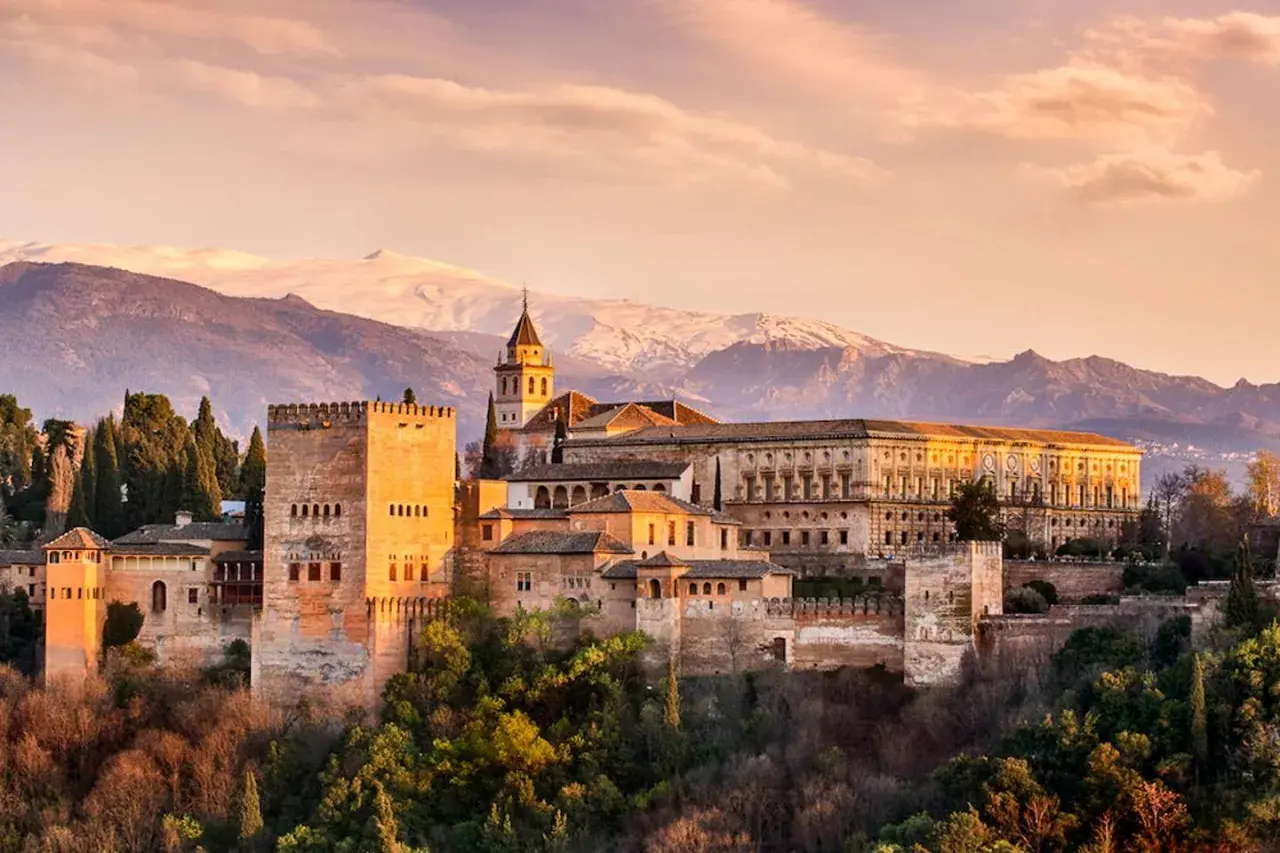 Die Alhambra in Granada, ein Ort voller Geschichte und **Granada Geheimtipps**, thront vor schneebedeckten Bergen.