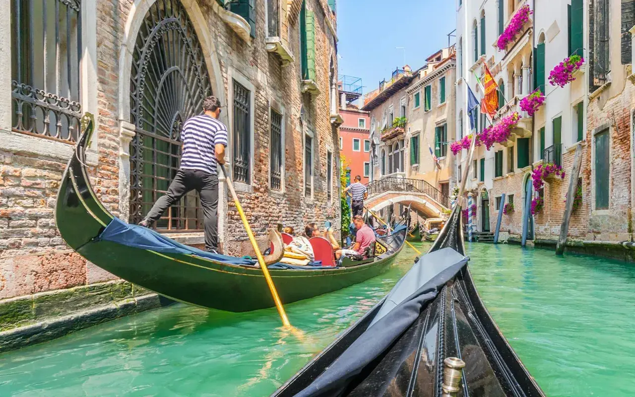 En gondoltur i Venedig är en dröm för många. Undrar du vad kostar det att åka gondol i Venedig? Här ser du en gondol som glider fram på kanalen.