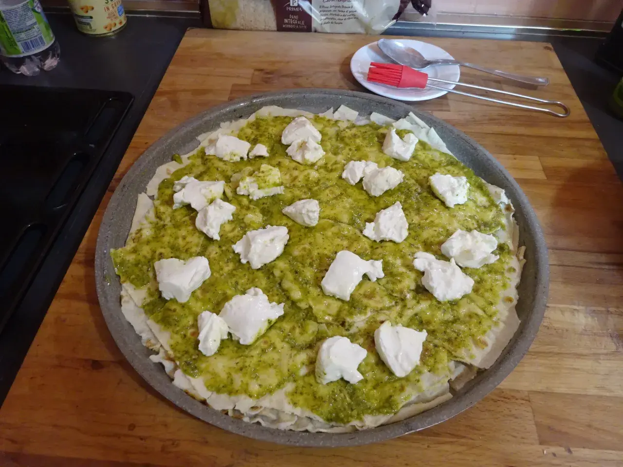 Une pizza à la pâte fine, recouverte de sauce verte et de morceaux de fromage blanc. Un délice inspiré du pain sarde.