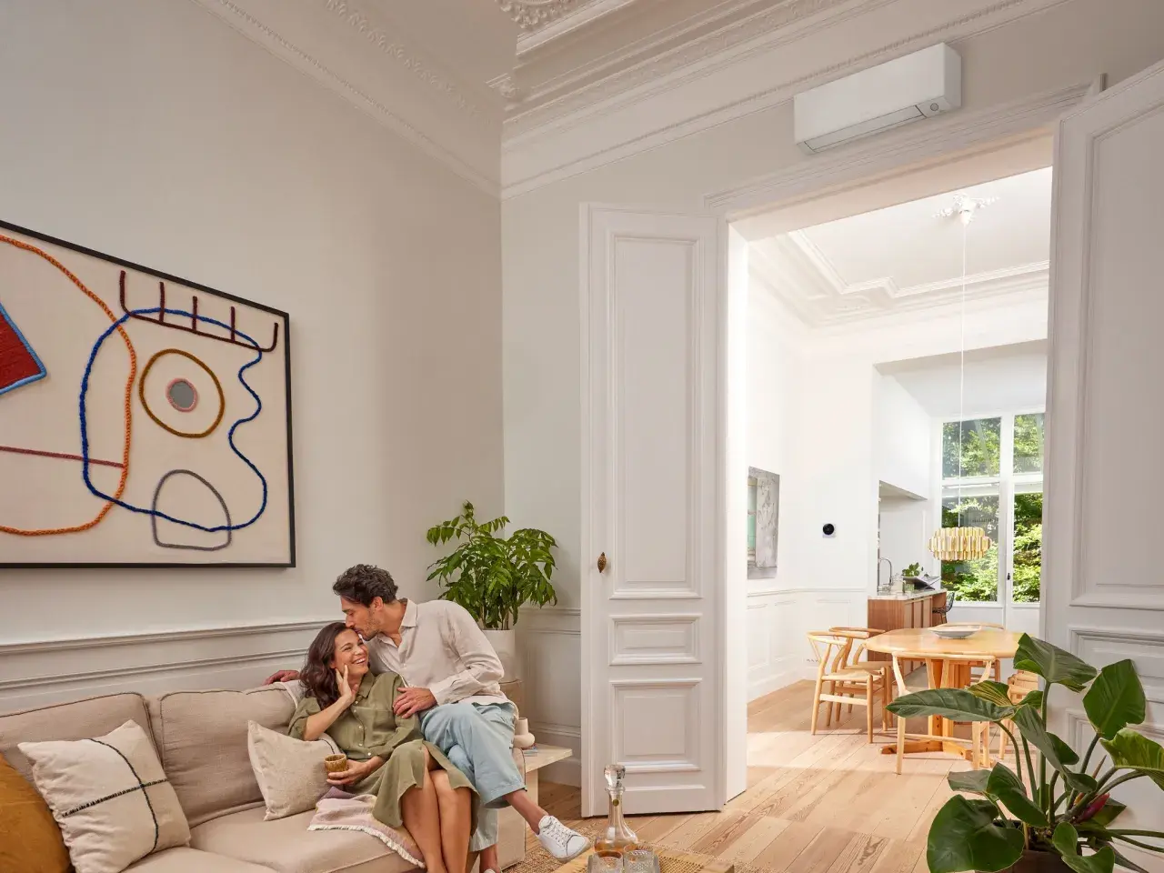 Pareja feliz en un salón moderno. El aire acondicionado Daikin, símbolo de calor confortable, se ve en la pared.