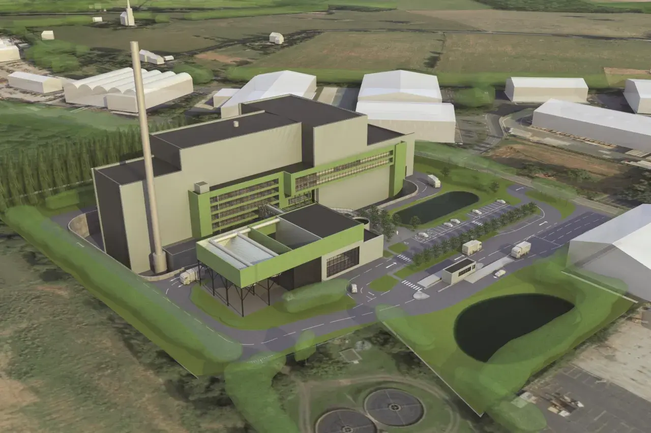An aerial view of a modern industrial facility, likely a waste-to-energy plant, designed by Valmet Inc. The complex features a tall smokestack, large grey and green buildings, a parking lot with trucks, and surrounding green spaces.