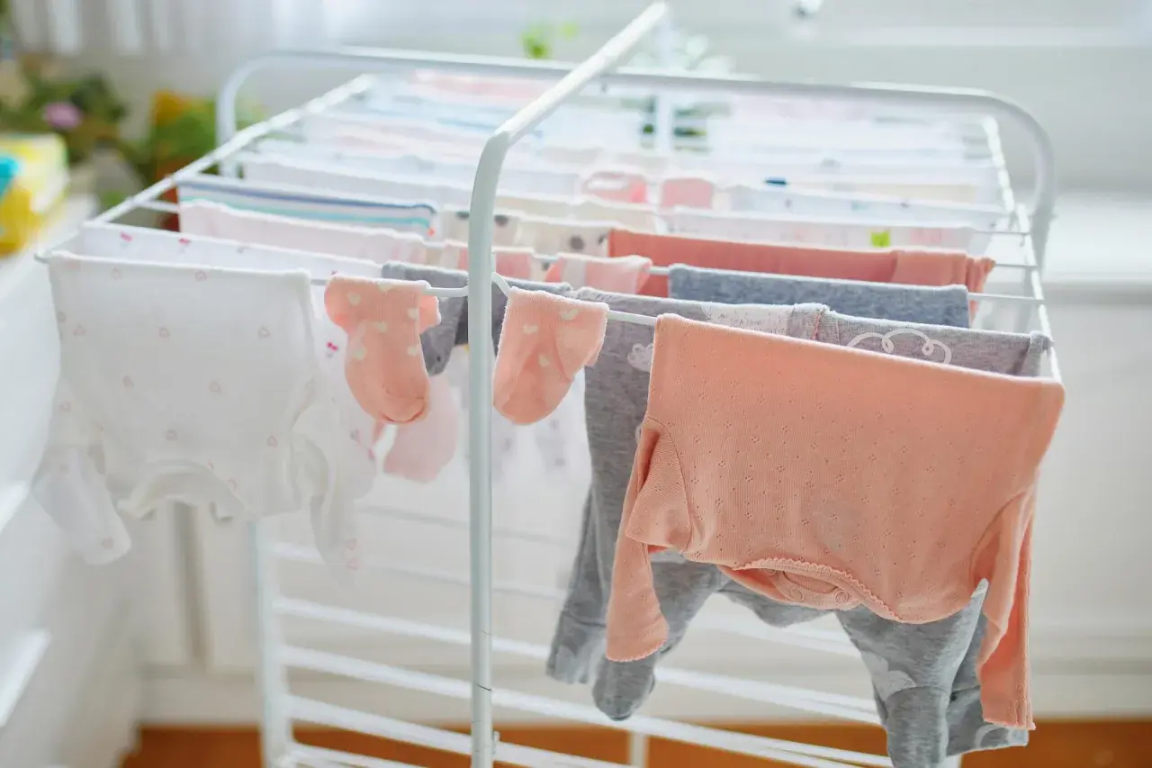 Suszenie ubranek dla noworodka na suszarce. Czy trzeba prasować ubranka dla noworodka? Delikatne body i skarpetki schną, czekając na maluszka.