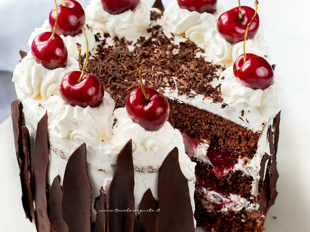 Una fetta di foresta nera torta, con panna montata, ciliegie e scaglie di cioccolato.