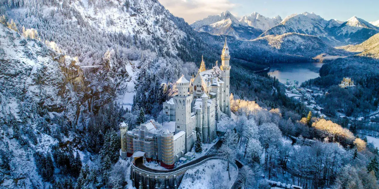 Schloss Neuschwanstein im winterlichen Glanz, ein märchenhafter Ort für einen Urlaub im Dezember. Schnee bedeckt die Berge und Bäume.