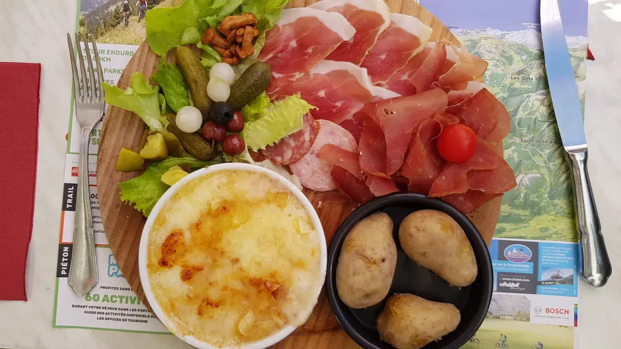 Assiette généreuse de charcuterie, fromage gratiné, pommes de terre et crudités, un vrai plat savoyard pour les gourmands.