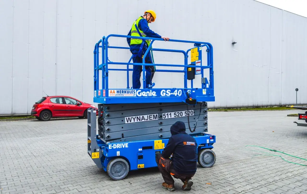 Dwóch pracowników w kaskach i kamizelkach na podnośniku koszowym Genie GS-40.