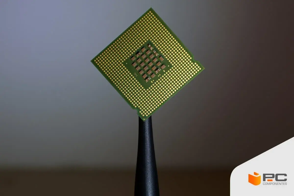 Procesador Intel Core i5, con sus pines dorados y el chip central visible, sostenido por una herramienta.