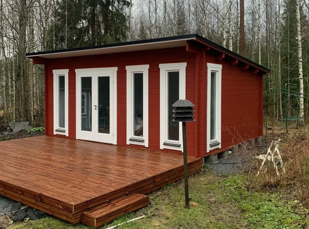 Rött attefallshus med altan i skogsglänta. Perfekt för dig som vill bygga attefallshus och njuta av naturen.