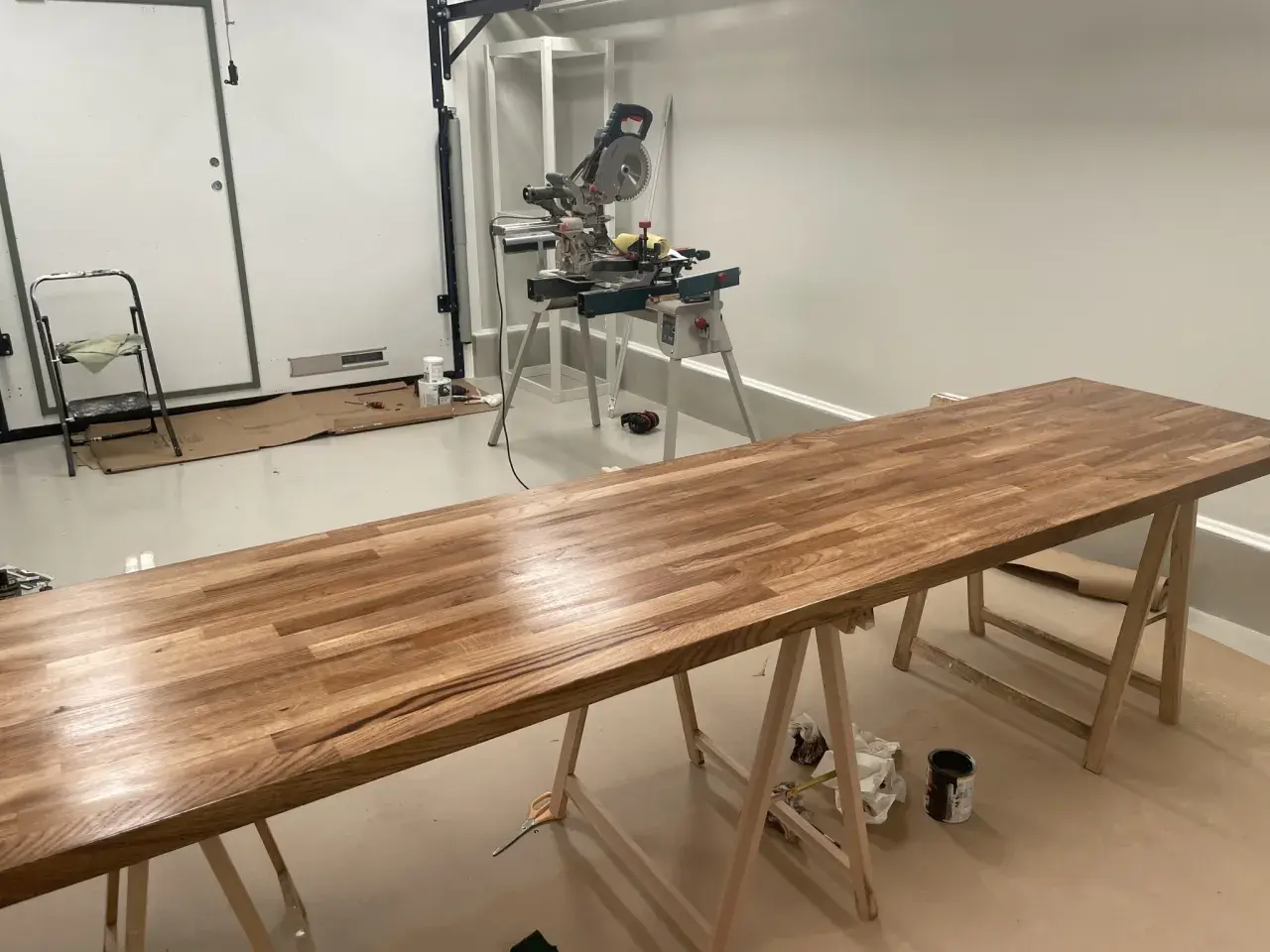 Långt ekbord på sågbockar, redo att behandla ekbordet. Kap- och geringssåg i bakgrunden.