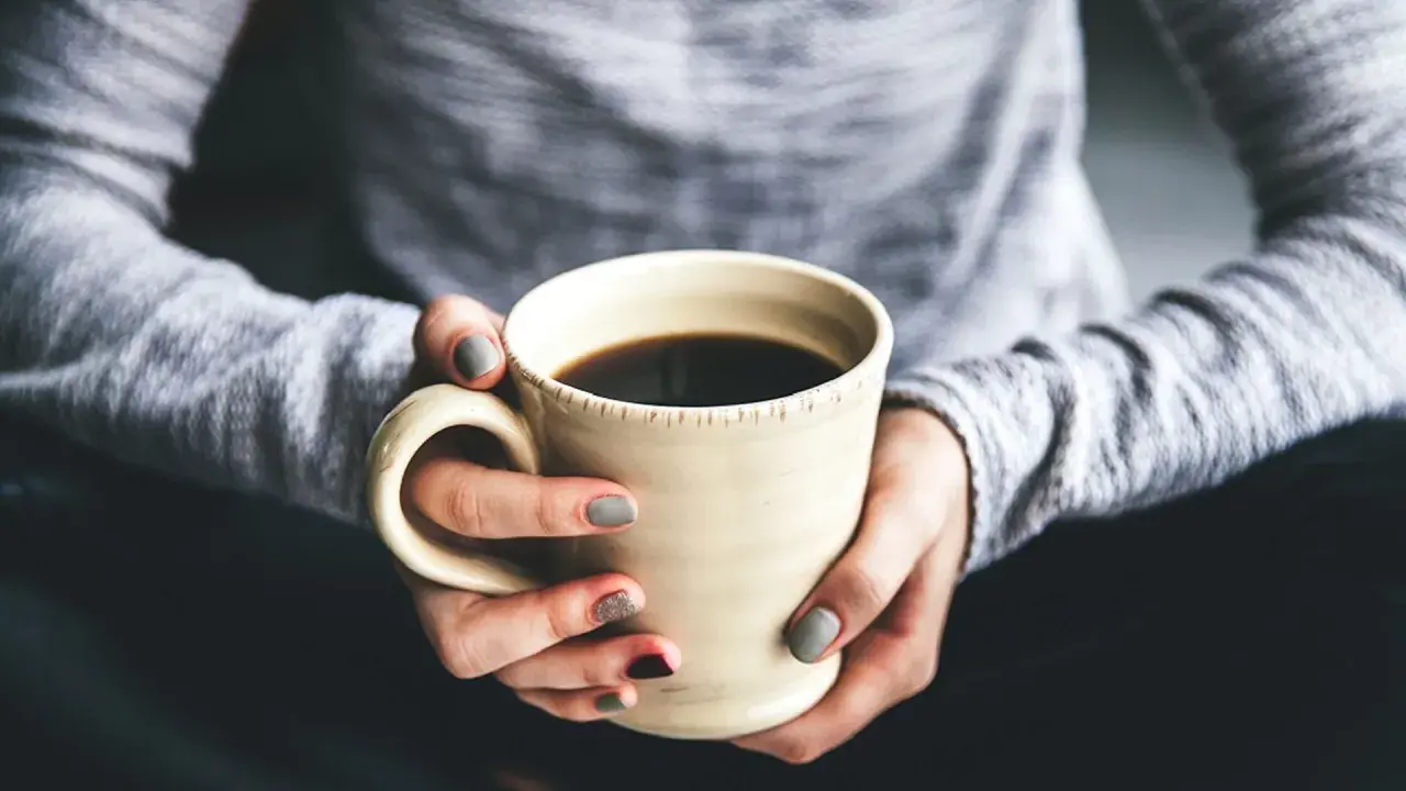 Dłonie trzymają kubek z kawą. Chcesz wiedzieć, jak zrobić kawę rozpuszczalną Nescafé? To proste!
