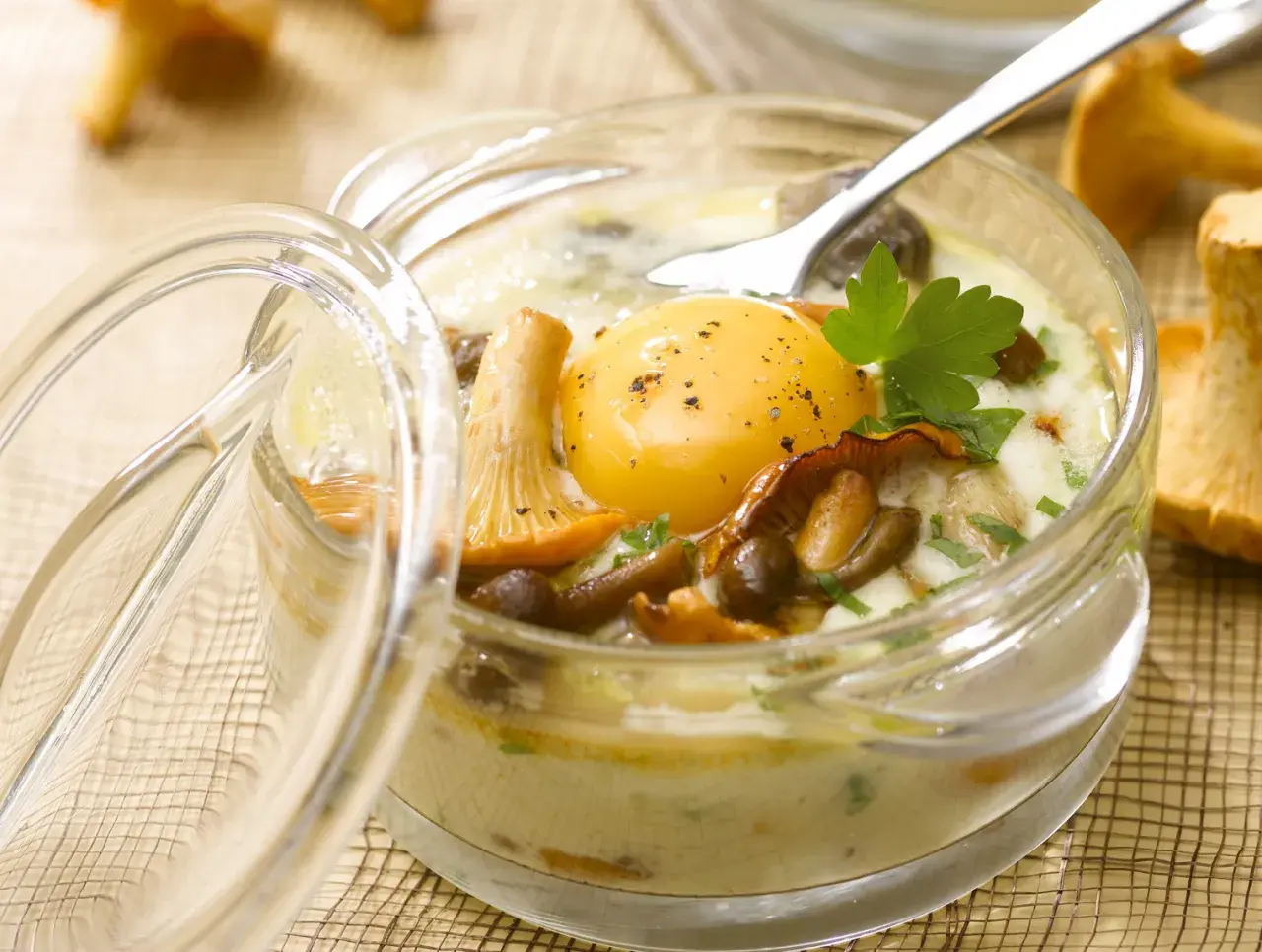 Un œuf au plat, entouré de champignons et de persil, dans un ramequin en verre. Un plat savoureux d'œufs au four.