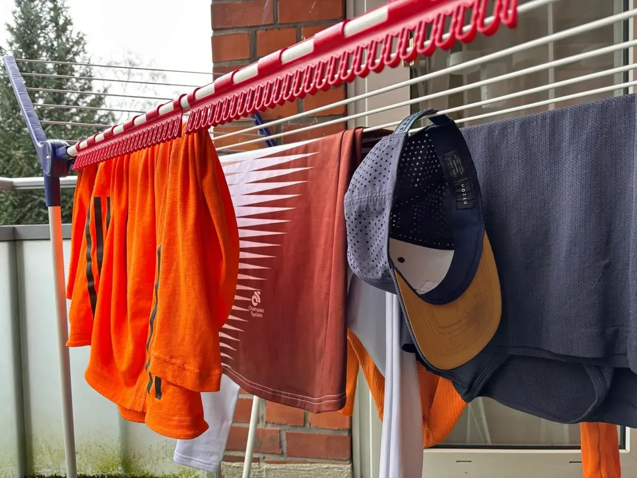 Wäscheleine mit Kleidung, darunter eine orangefarbene Sportbekleidung und eine Kappe zum Reinigen.