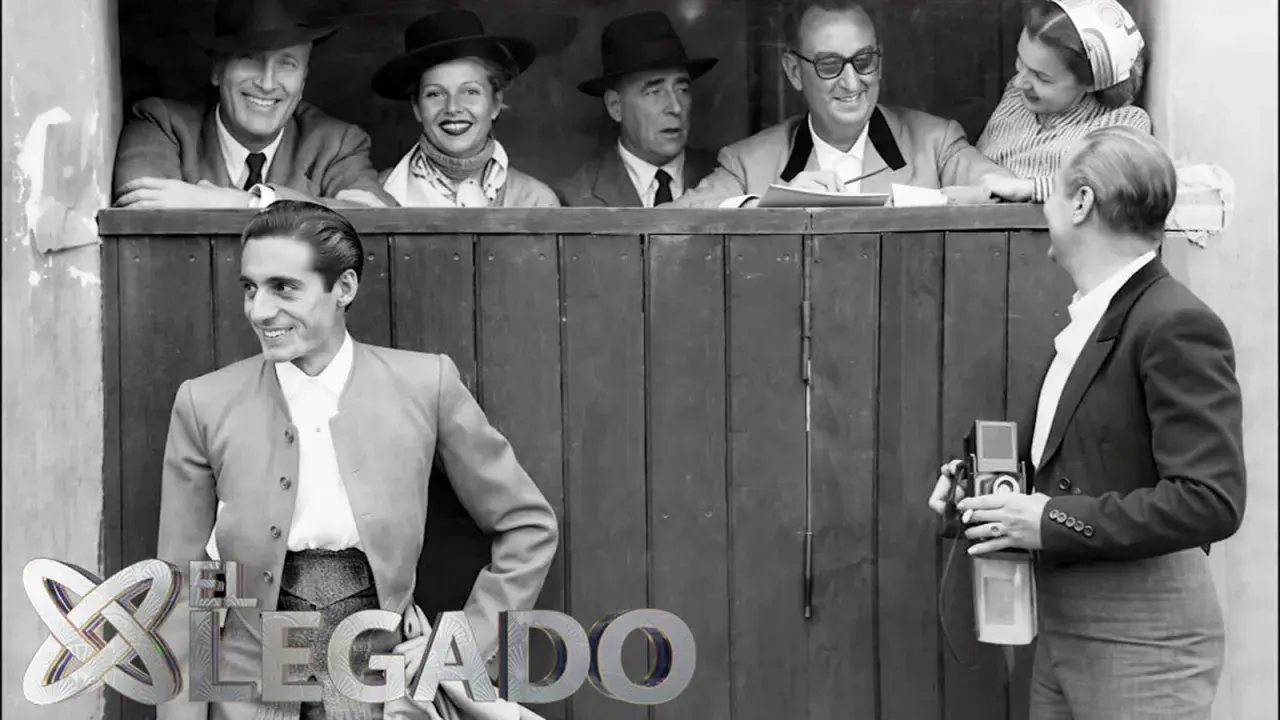 Un torero posa sonriente, mientras un fotógrafo captura el momento. Detrás, un grupo de espectadores, evocando la época de los toreros de los 90.