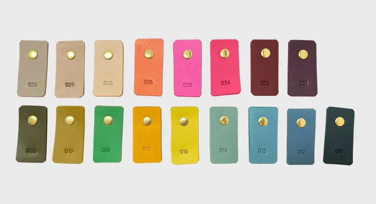 Échantillons de cuir aux teintes variées, du beige au prune, en passant par des couleurs vives comme le rose et l'orange. Chaque pièce présente une couleur de cuir distincte.