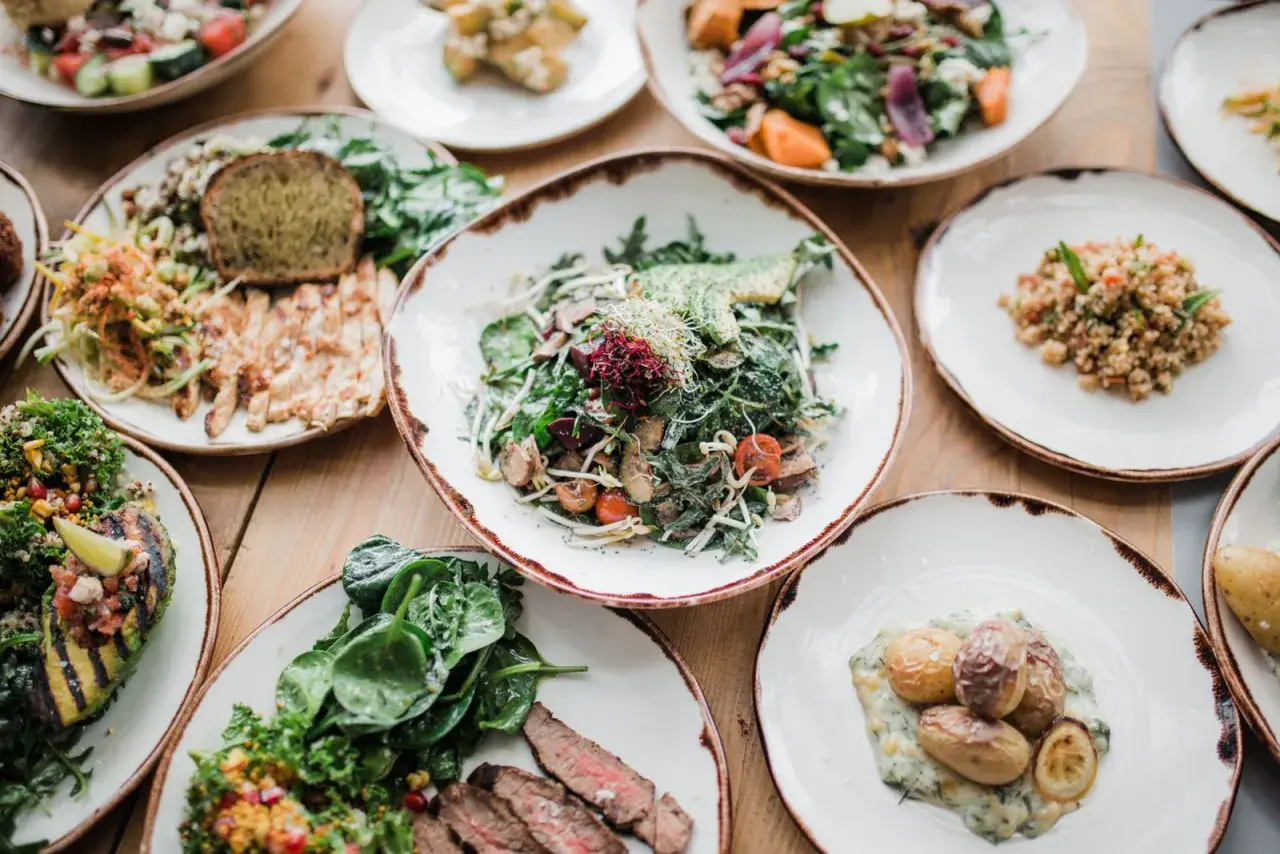 Variedad de platos saludables, incluyendo una ensalada de verdel con aguacate, pollo a la parrilla, quinoa y patatas asadas.