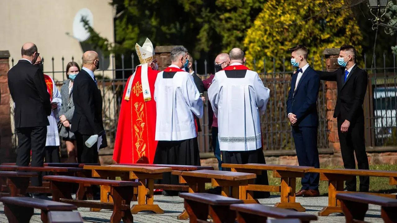 Biskup w czerwonej kapie i ministranci podczas ceremonii bierzmowania.