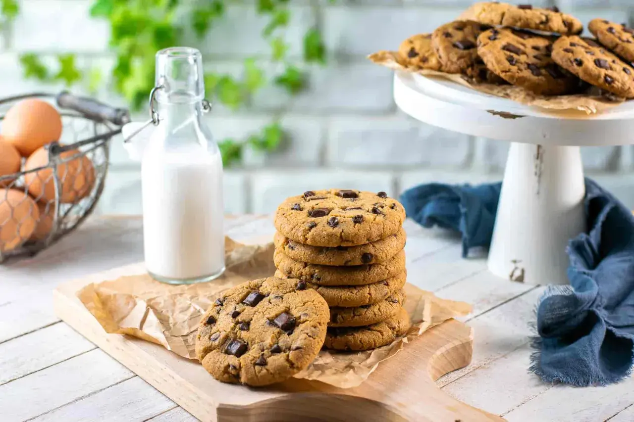 Una pila di biscotti con gocce di cioccolato, pronti per essere gustati con un bicchiere di latte.