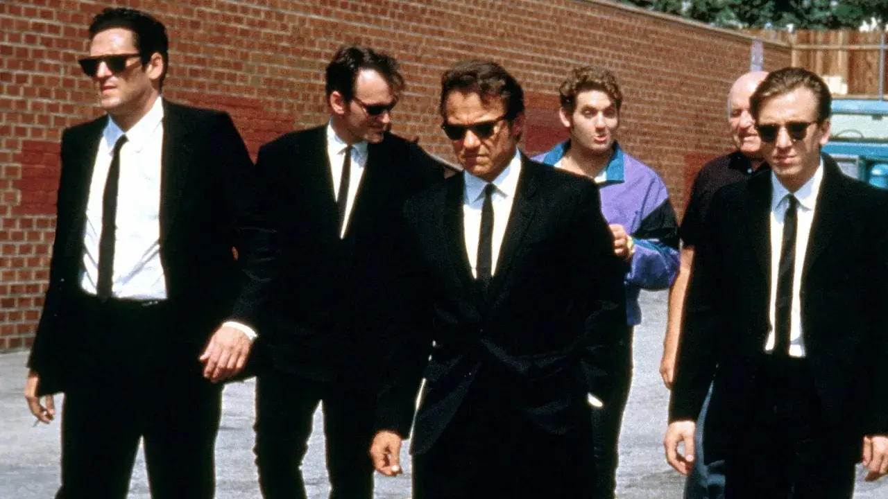 Sei uomini in abito nero camminano in gruppo, un cast cinematografico iconico.