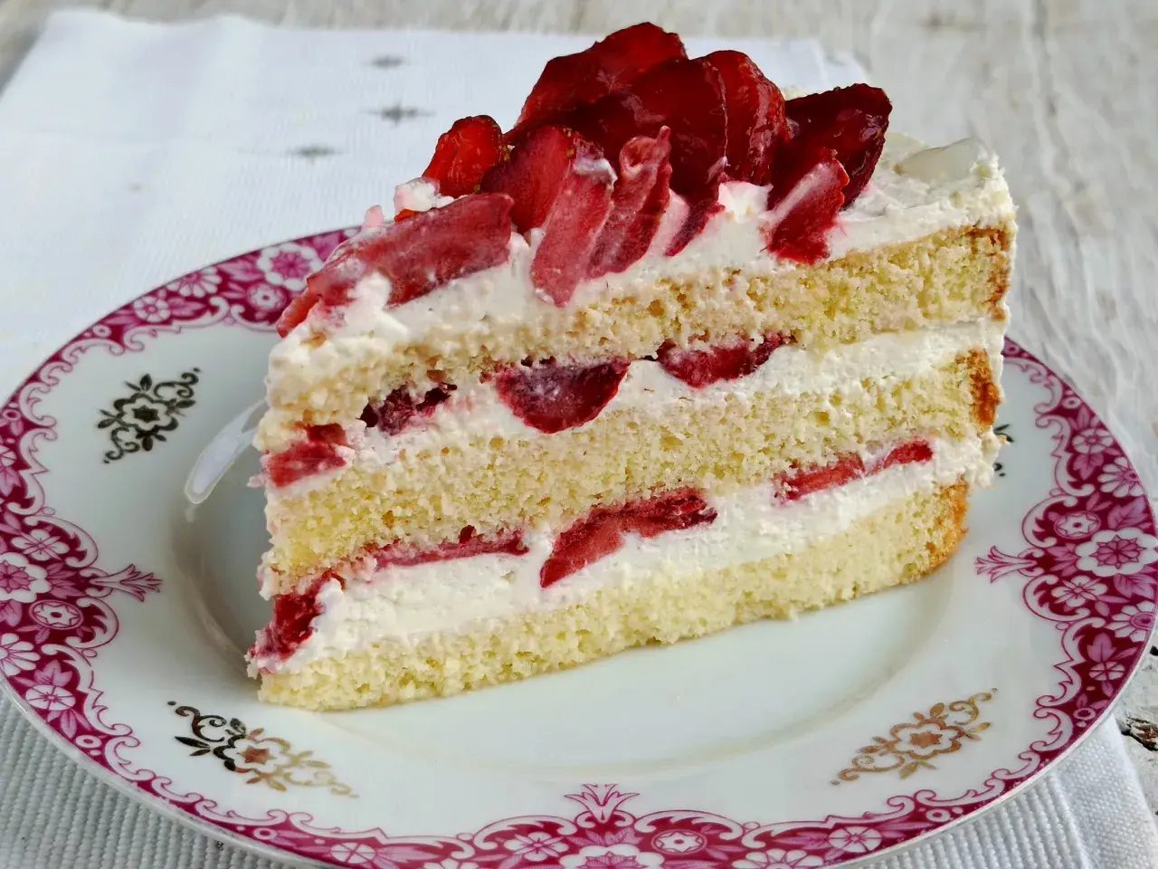 Pyszny biszkopt z serkiem mascarpone i bitą śmietaną, przełożony truskawkami. Idealny deser na każdą okazję.