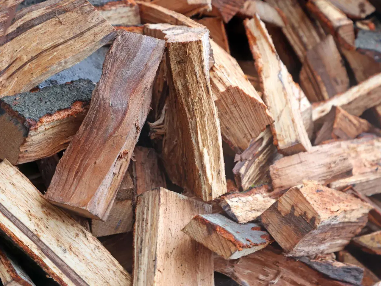 Stapel von gespaltenem Brennholz, bereit für den Kamin. Das Holz zeigt die Maserung und Rinde, die den hohen Brennwert beeinflussen.