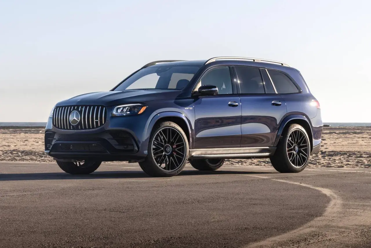 Lśniący, granatowy Mercedes-Benz GLS z czarnymi felgami stoi na asfalcie przy plaży.