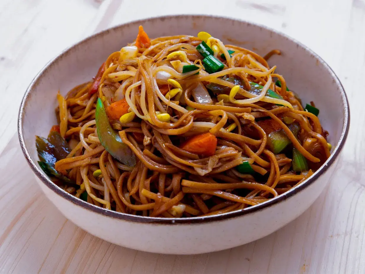 En skål med utsökt chow mein, full av nudlar, grönsaker och böngroddar.