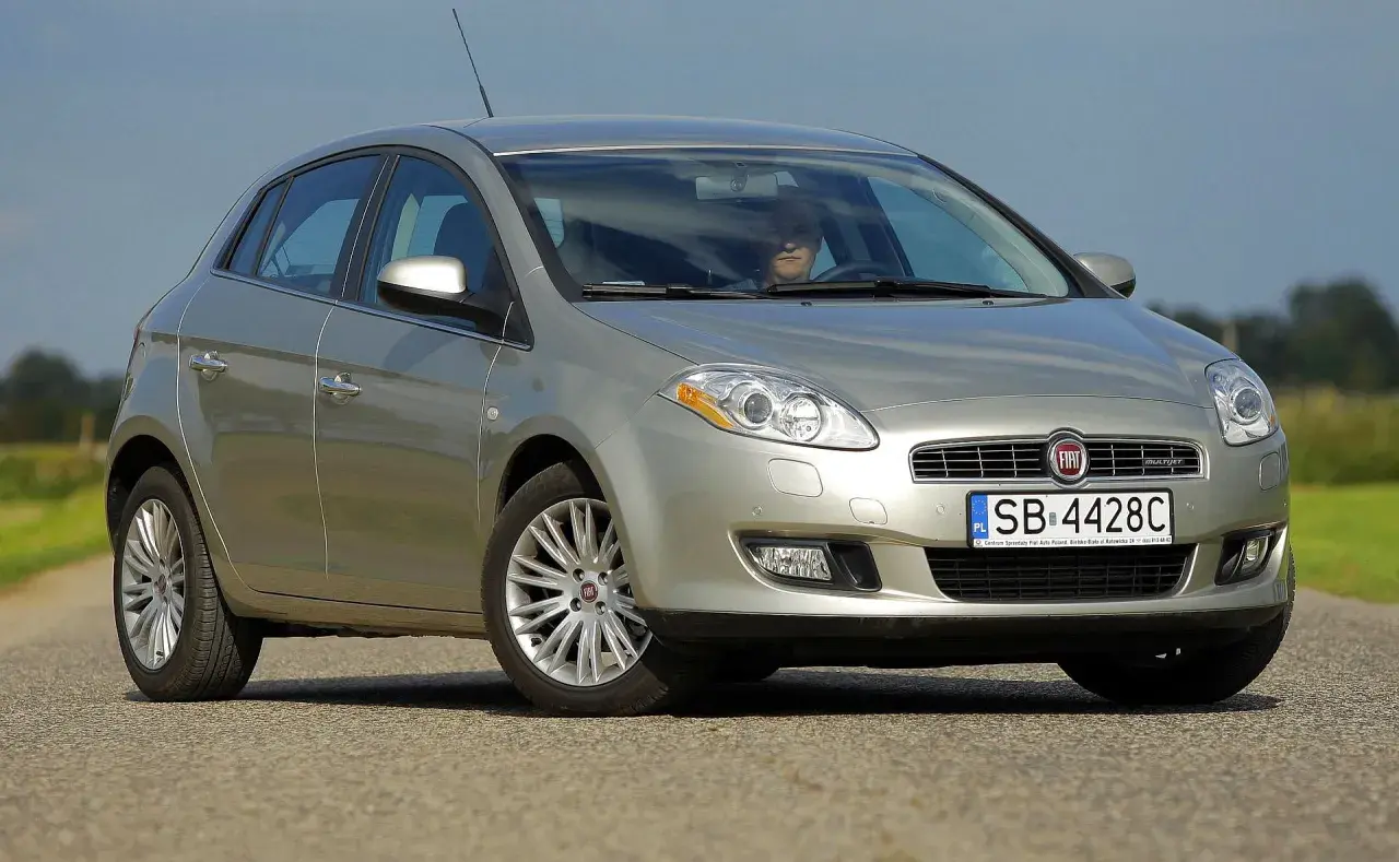 Srebrny Fiat Bravo 2 z wyraźnymi żarówkami reflektorów, zaparkowany na drodze.