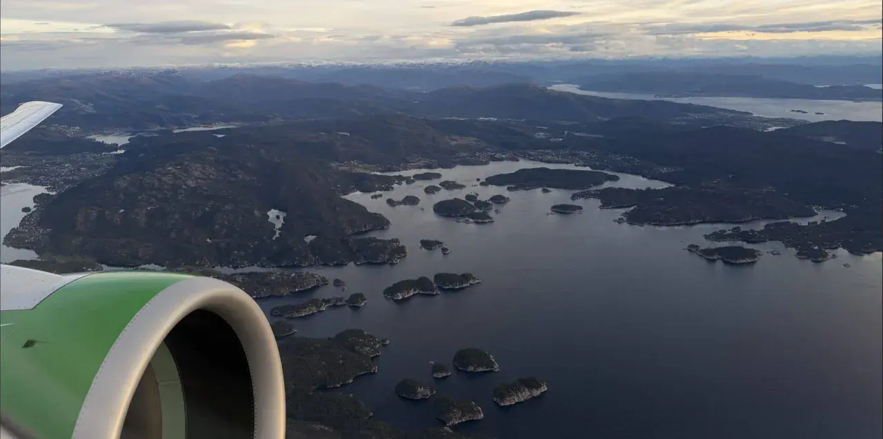 Flugzeugfenster mit Blick auf norwegische Schärenlandschaft. Gute Widerøe Airline Erfahrungen auf dieser Route.