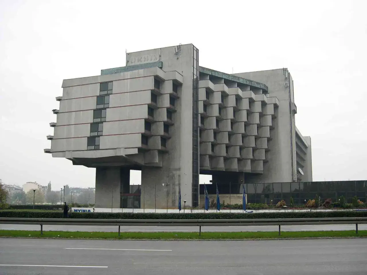 Monumentalny budynek w stylu brutalizm, z betonową fasadą i charakterystycznymi, wystającymi elementami.